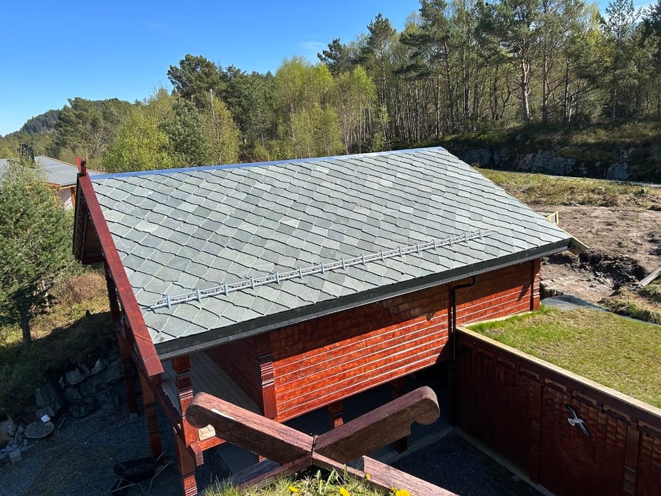 Ferdig lagt skifertak med Stilla-skifer på hyttegarasje i Hellevik, omgitt av vestlandsnatur