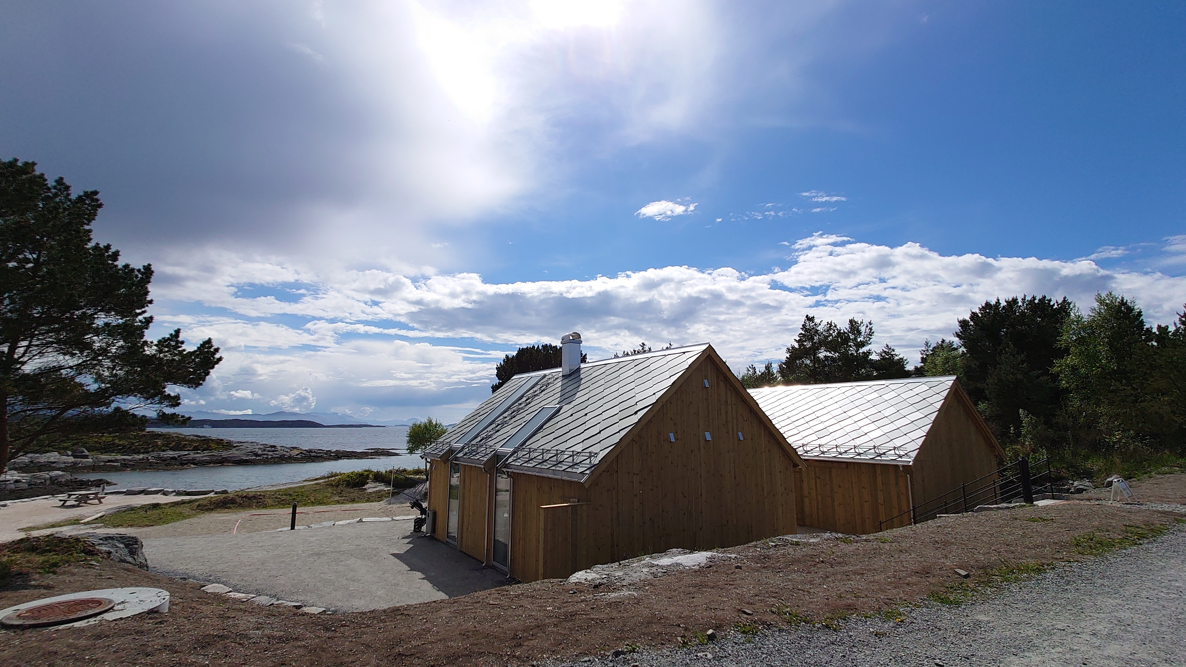 Kafe og servicebygg på Sørstrand med nytt skifertak fra NorSkifer, midt i kystlandskapet.